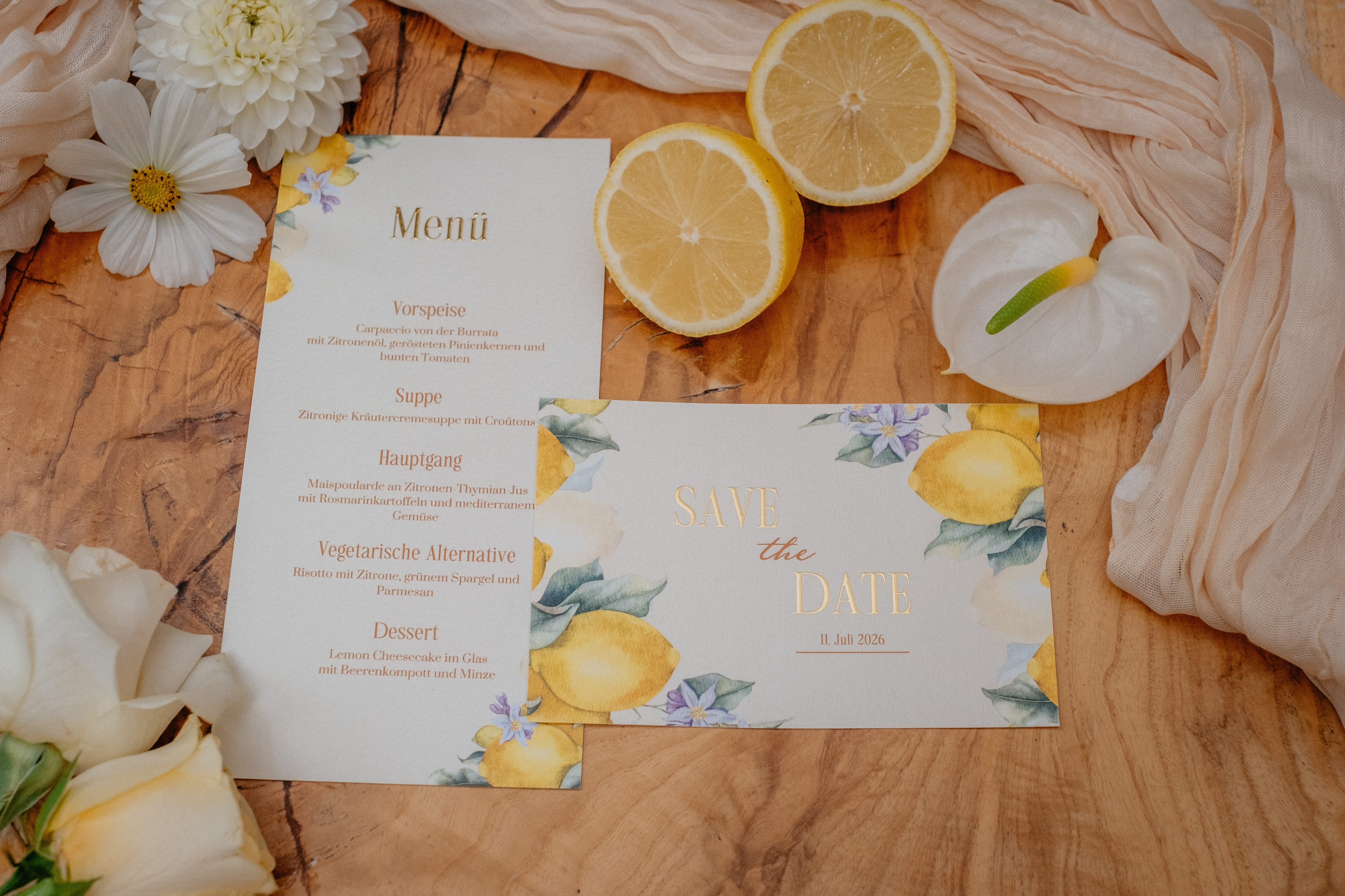 Menükarte und Save-the-Date-Karte mit Zitronen-Motiv auf einem Holztisch