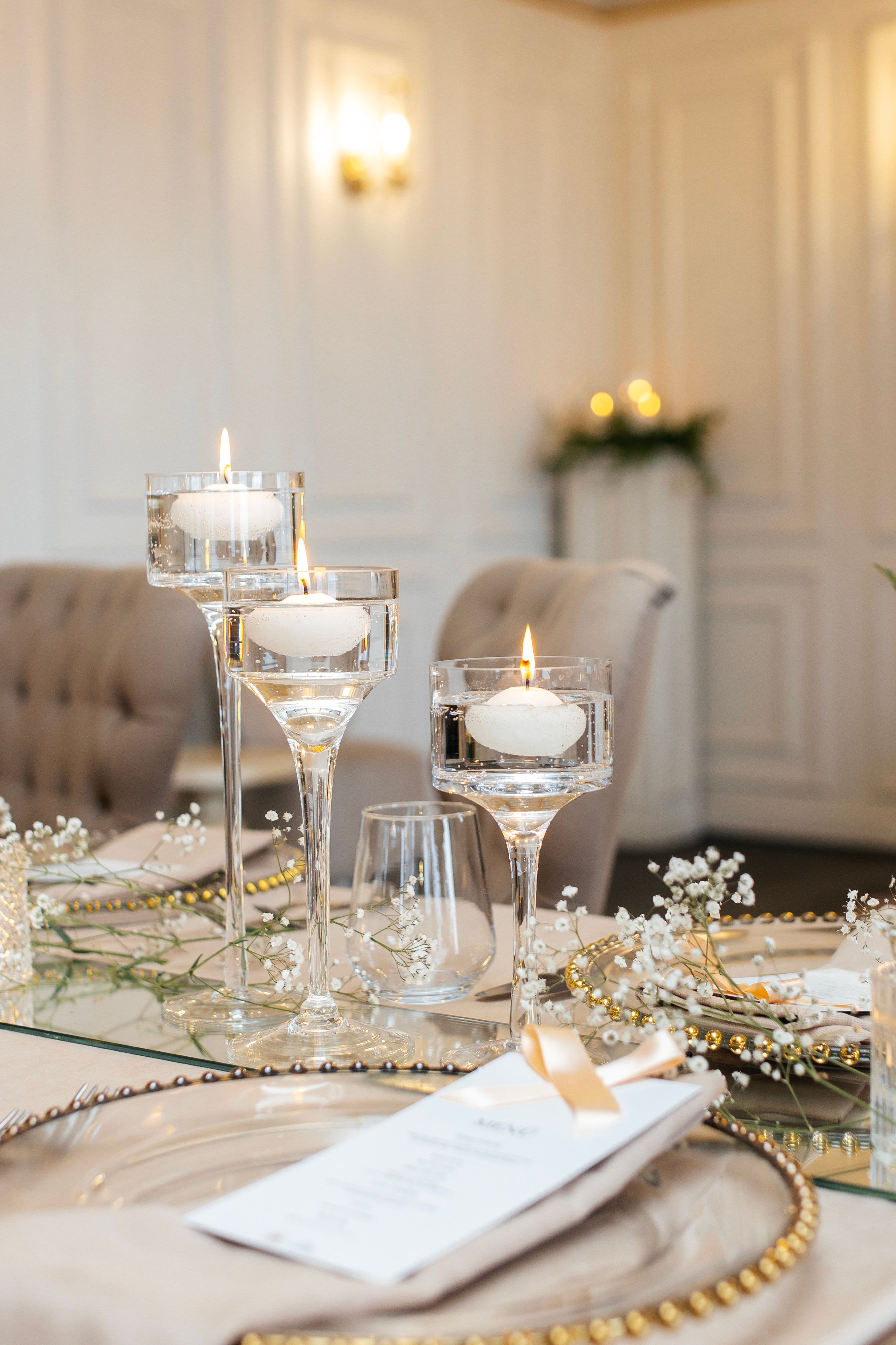 Festlich gedeckte Tafel mit Schwebekerzen, Schleierkraut und goldenen Details